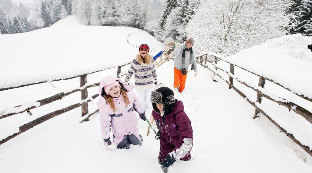 Familie beim Rodeln im Winter