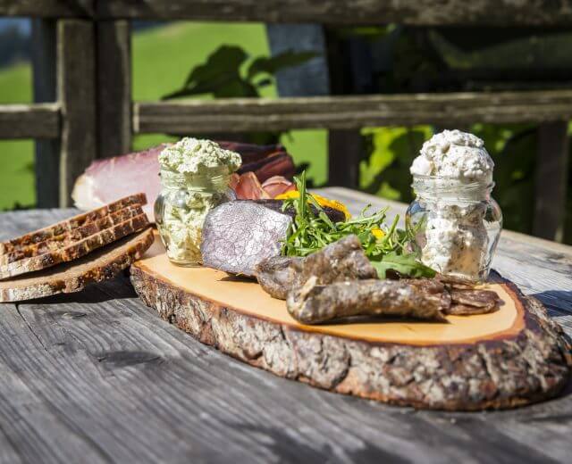 Jause am Holzbrett serviert mit Wurst, Speck und Brot