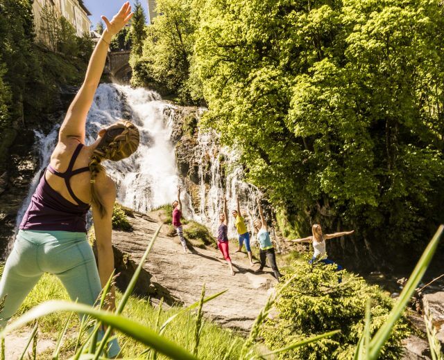 Gruppe macht Morgenyoga am Wasserfall