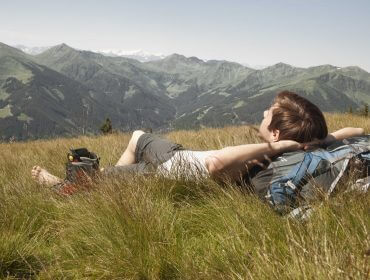 Mann entspannt auf Wanderung im Gras