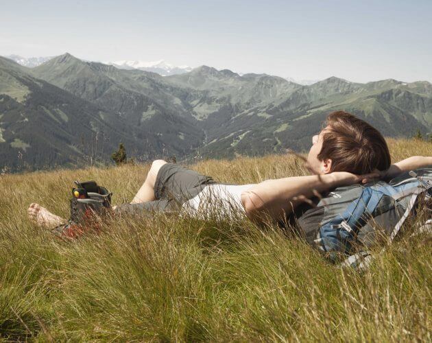 Mann entspannt auf Wanderung im Gras