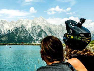 Zwei Biker sitzen vor einer traumhaften Kulisse aus See und Berg in Saalfelden Leogang