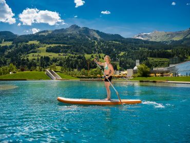 Frau am SUP-Board auf Thermalwasser-Badesee