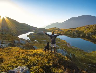 Mann mit Hund steht vor einem Lungauer Bergsee