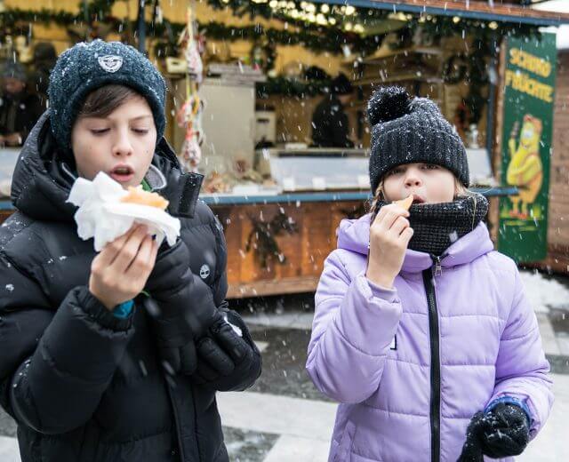 Entdecker-Bambini-con-la-Valigia Simone und Siria probieren die Schmankerl auf den Adventmärkten