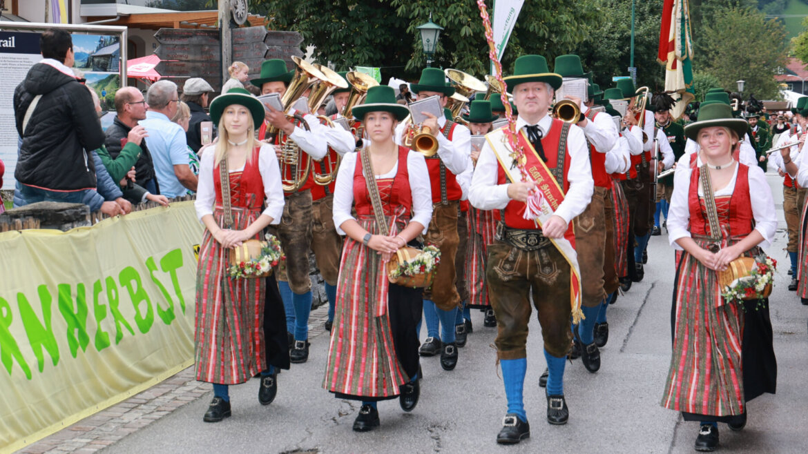 Ein Spielmannszug in traditioneller österreichischer Tracht zieht bei einem Fest im Freien an den Zuschauern vorbei. (vergrößerte Ansicht)