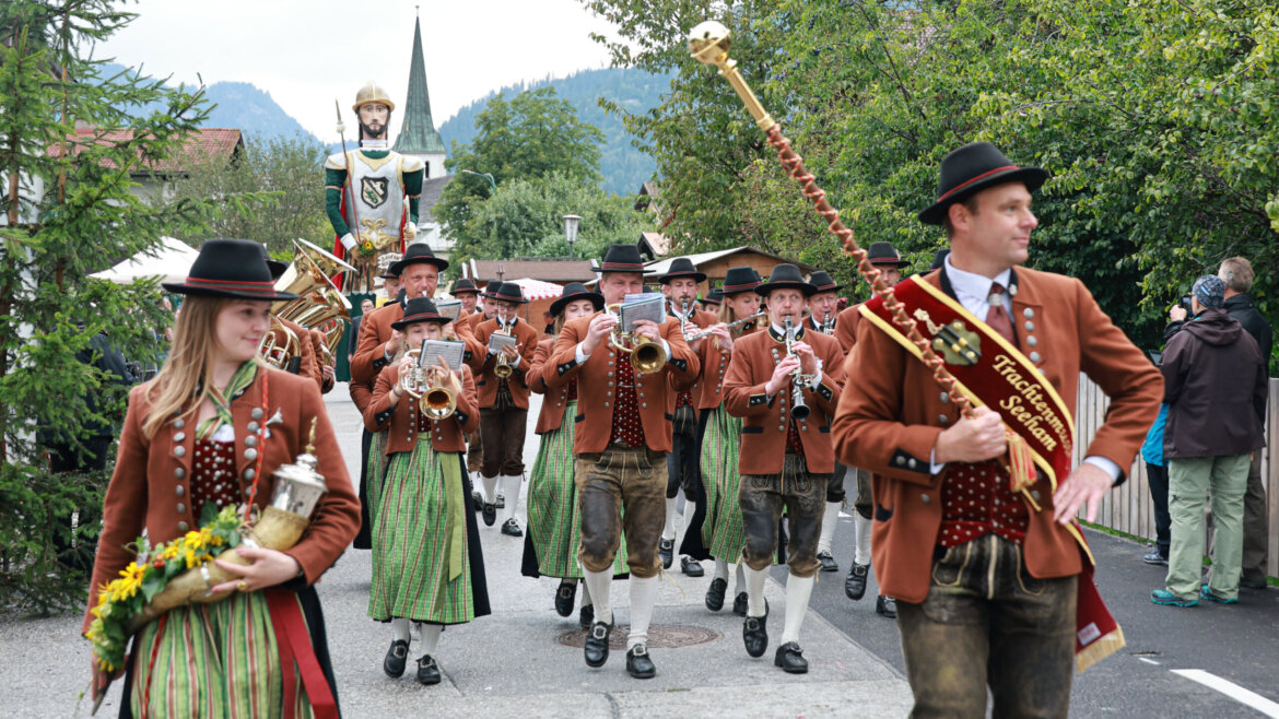 Ein Spielmannszug in traditioneller österreichischer Tracht spielt bei einer festlichen Parade im Freien. (vergrößerte Ansicht)