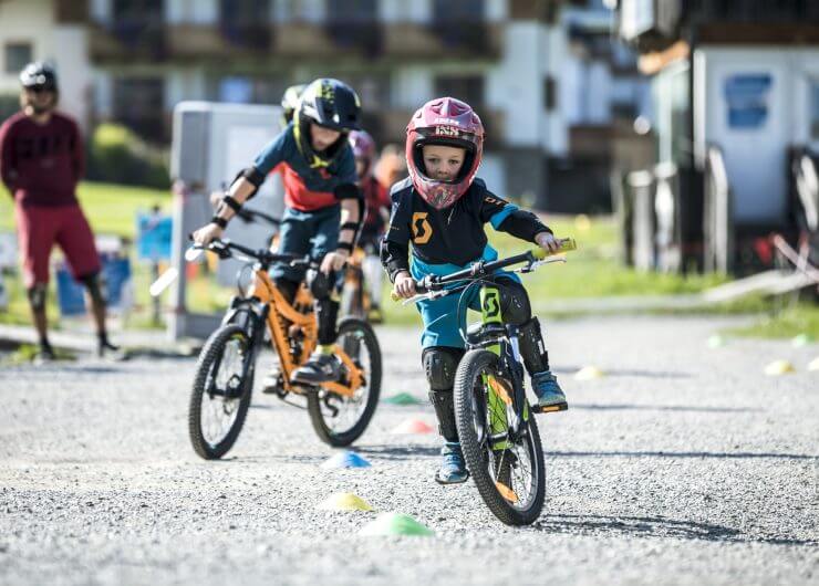 Kinder mit Helm am Mountainbike im Bikepark
