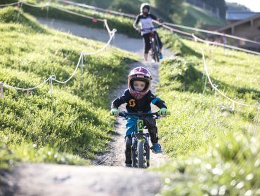 Kinder mit Helm am Mountainbike im Bikepark