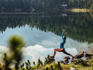 Yoga am Reedsee Eine Person, die in der Nähe eines ruhigen Sees Yoga praktiziert - ein toller Moment, wenn sich Berge und Bäume im Wasser spiegeln.