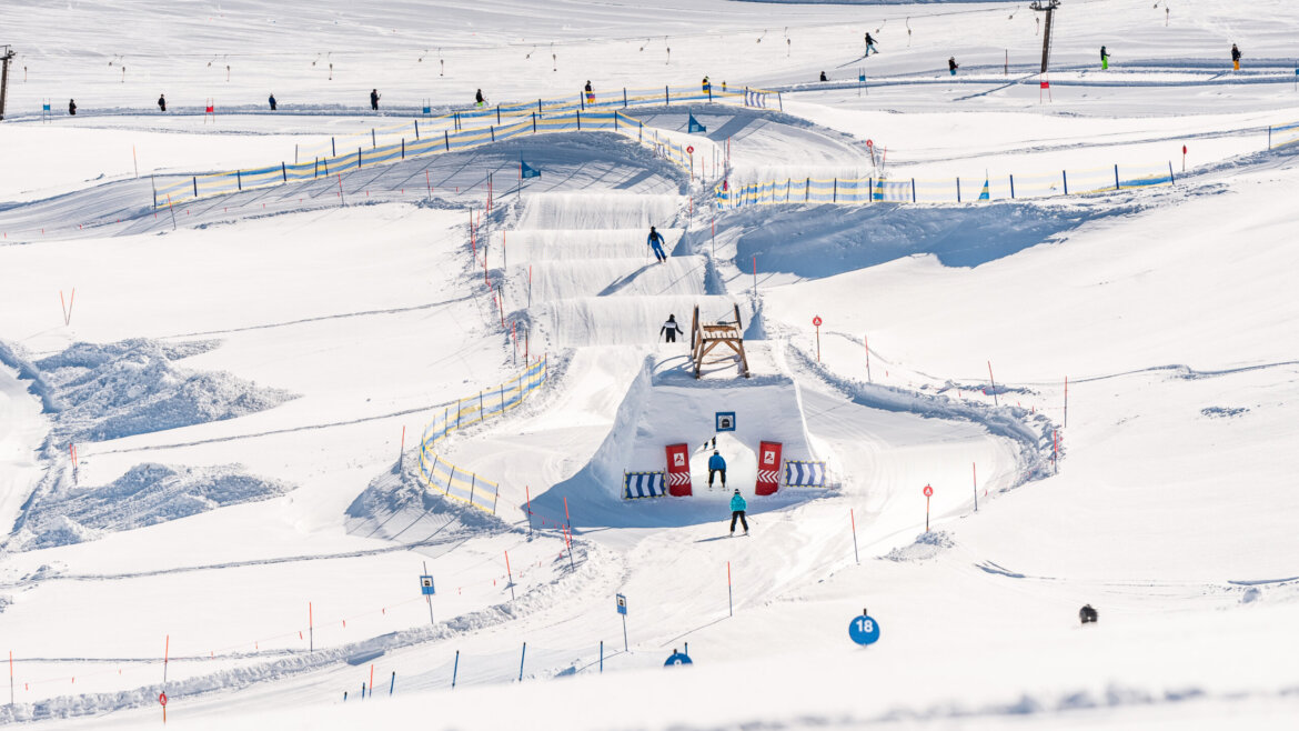 Die Skifahrer rasen unter der Wintersonne die verschneite Skicross-Strecke des Wildkogels mit aufregenden Sprüngen und scharfen Kurven hinunter. (vergrößerte Ansicht)