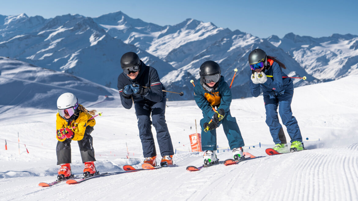 Vier Personen beim Skifahren am Wildkogel, verschneite Pisten mit Bergen und blauem Himmel im Hintergrund. (vergrößerte Ansicht)