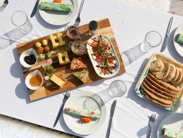 Kulinarische Hofwanderung (C) KTVB Hofgastein; Marktl Photography-16578 Ein Picknicktisch im Gasteinertal mit Käse, Brot, Salat, Aufstrichen und Tellern für eine Mahlzeit im Freien.