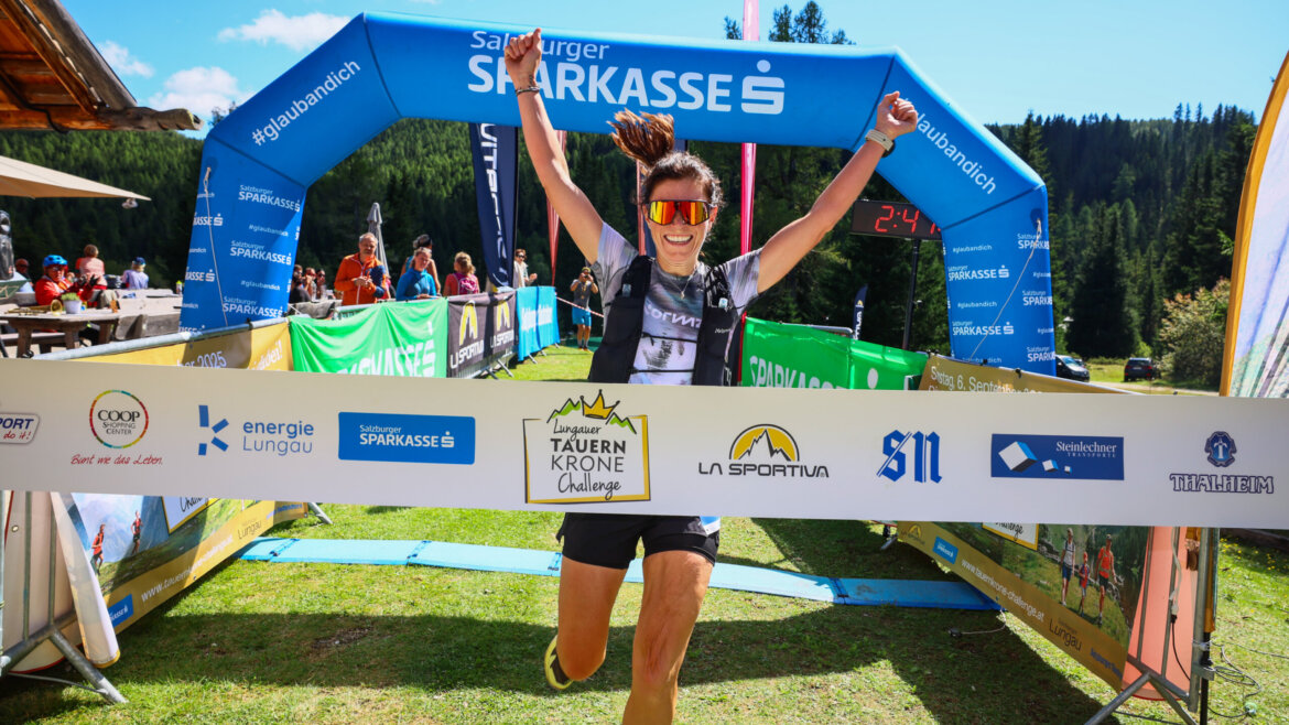 Ein Läufer überquert mit erhobenen Armen freudig die Ziellinie bei einem Trailrunning-Event im Freien. (vergrößerte Ansicht)