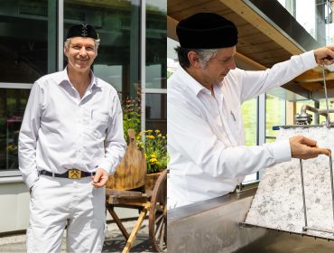 Ein Mann in weißer Kleidung und mit schwarzer Mütze steht draußen und arbeitet mit Salz in einer Anlage.