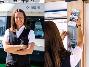 Eine lächelnde Frau in Uniform steht an einem Boot und ordnet Broschüren auf einem Regal im Inneren.