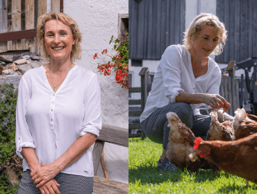 Frau in weißer Bluse, die an einer Bank lächelt und sich dann ins Gras hockt, um an einem sonnigen Tag draußen Hühner zu füttern.