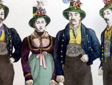 Vier Personen in traditioneller österreichischer Kleidung, darunter Hüte mit Federn und Schmuckwesten.