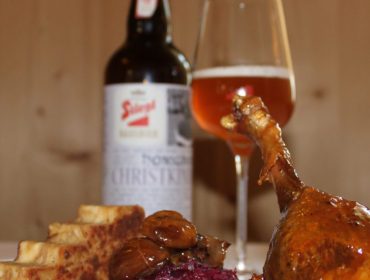 Gebratene Hühnerkeule mit Waffeln, Rotkohl und Bier auf einem Tisch in einem Holzzimmer.