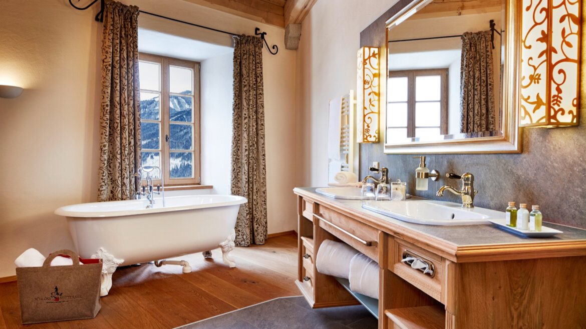 Badezimmer © Schloss Mittersill Elegantes Badezimmer mit freistehender Badewanne, Doppelwaschbecken, großem Spiegel und Blick auf Schloss Mittersill. (vergrößerte Ansicht)