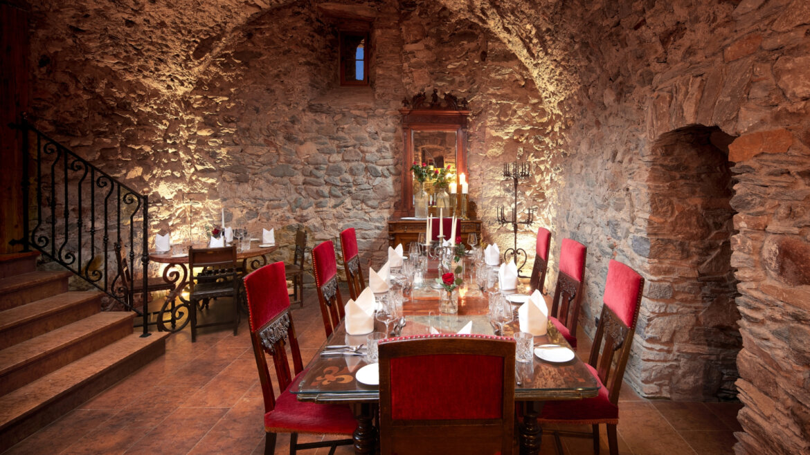 Gewölbekeller © Schloss Mittersill Elegant gedeckter Esstisch für eine Mahlzeit auf Schloss Mittersill, in einem rustikalen Steinsaal mit roten Stühlen und Kerzenlicht. (vergrößerte Ansicht)