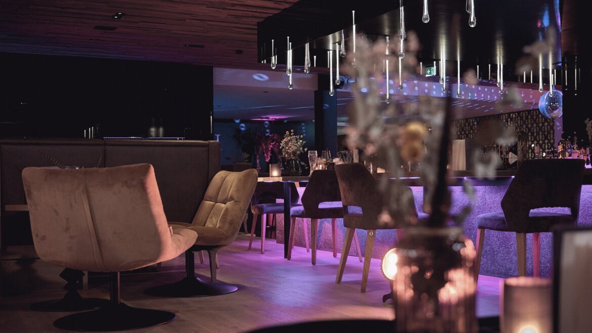 Moderne Lounge-Bar in der Hochkönigin mit Samtsesseln, lila Beleuchtung und Hängelampen für eine schicke Atmosphäre. (vergrößerte Ansicht)