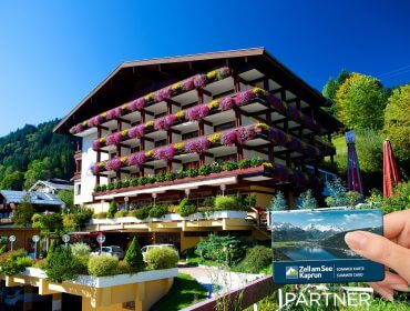Eine Hand hält eine Zell am See-Kaprun-Karte vor dem blumengeschmückten Sporthotel Alpin in den Alpen.