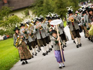 Trachtenmusikkapelle Ein Spielmannszug in traditioneller Kleidung spielt beim Bauernherbst-Umzug auf einer Landstraße.