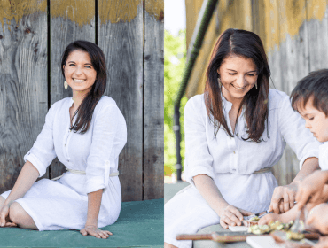 Frau im weißen Kleid lächelt, dann bereitet sie mit einem kleinen Kind im Freien Essen zu.