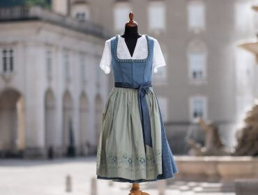 Ein traditionelles österreichisches Dirndlkleid, ausgestellt auf einer Schaufensterpuppe auf einem europäischen Platz.