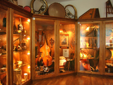 Eine mit verschiedenen Musikinstrumenten gefüllte Vitrine in einem warm beleuchteten Museumsraum.