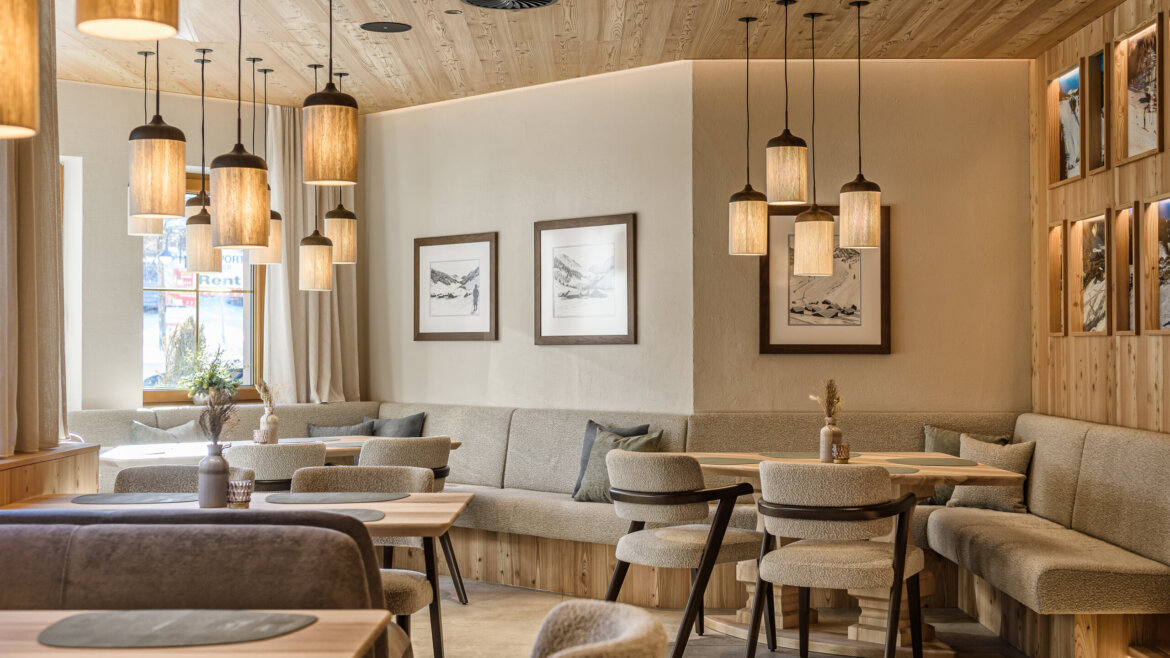 Gemütliches Restaurant mit Holzdekor, Hängelampen, gepolsterten Sitzgelegenheiten und gerahmter Kunst an den Wänden. (vergrößerte Ansicht)