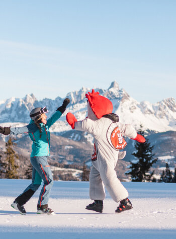 Eine Person gibt dem roten Maskottchen 