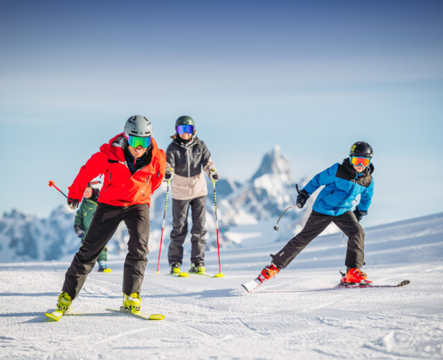 Familien Skilauf montepopolo (c) Snow Space Salzburg – Christoph Huber Familie mit Skiern an sonnigen Tag beim Anschieben in einem etwas flacheren Gelände.