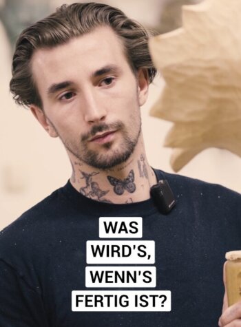 Ein Mann mit Tätowierungen am Hals hält einen hölzernen Gegenstand; Salzburger Almenweg Stories in deutscher Schrift.