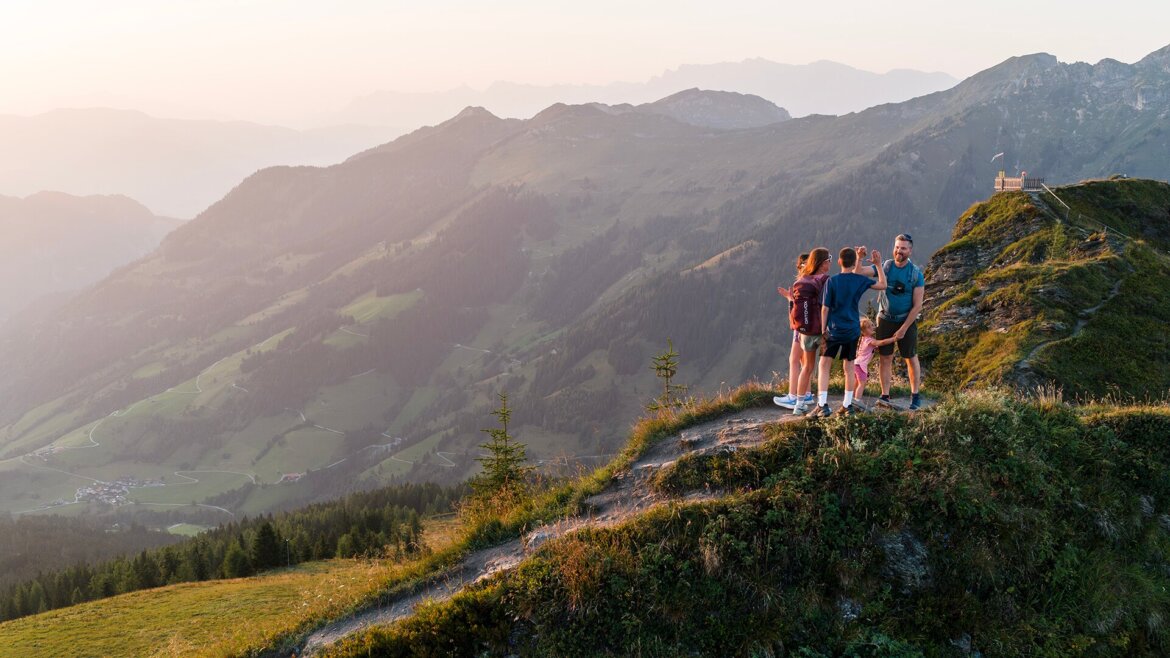 © Dorfgasteiner Bergbahnen AG, Erlebnisberg Fulseck Fünf Menschen stehen auf dem Erlebnisberg Fulseck in Dorfgastein, umgeben von malerischen Tälern und fernen Gipfeln bei Sonnenuntergang. (vergrößerte Ansicht)