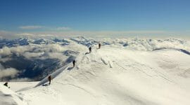 a group of people riding skis down a snow covered mountain