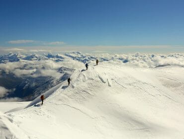 a group of people riding skis down a snow covered mountain