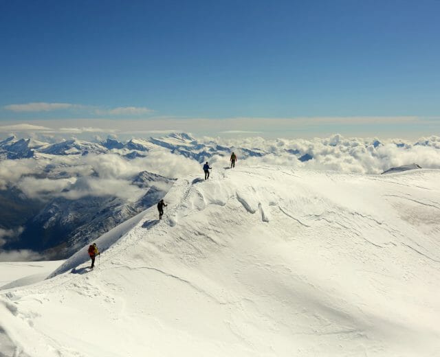 a group of people riding skis down a snow covered mountain