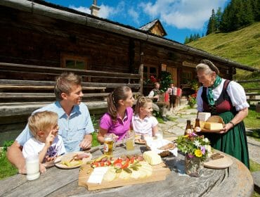 Hüttenwirtin serviert Familie frische Almprodukte.