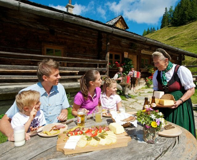 Hüttenwirtin serviert Familie frische Almprodukte.