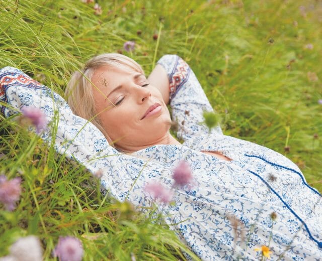 Alpine Gesundheit Junge Frau schläft auf der blühenden Almwiese
