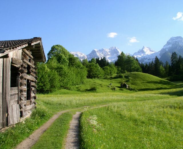 Weg über eine Wiese an einem Heuschober vorbei