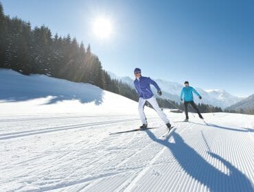 Two cross-country skier skating in the sun