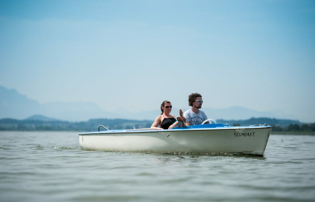 a man and a woman riding on the back of a boat in the water