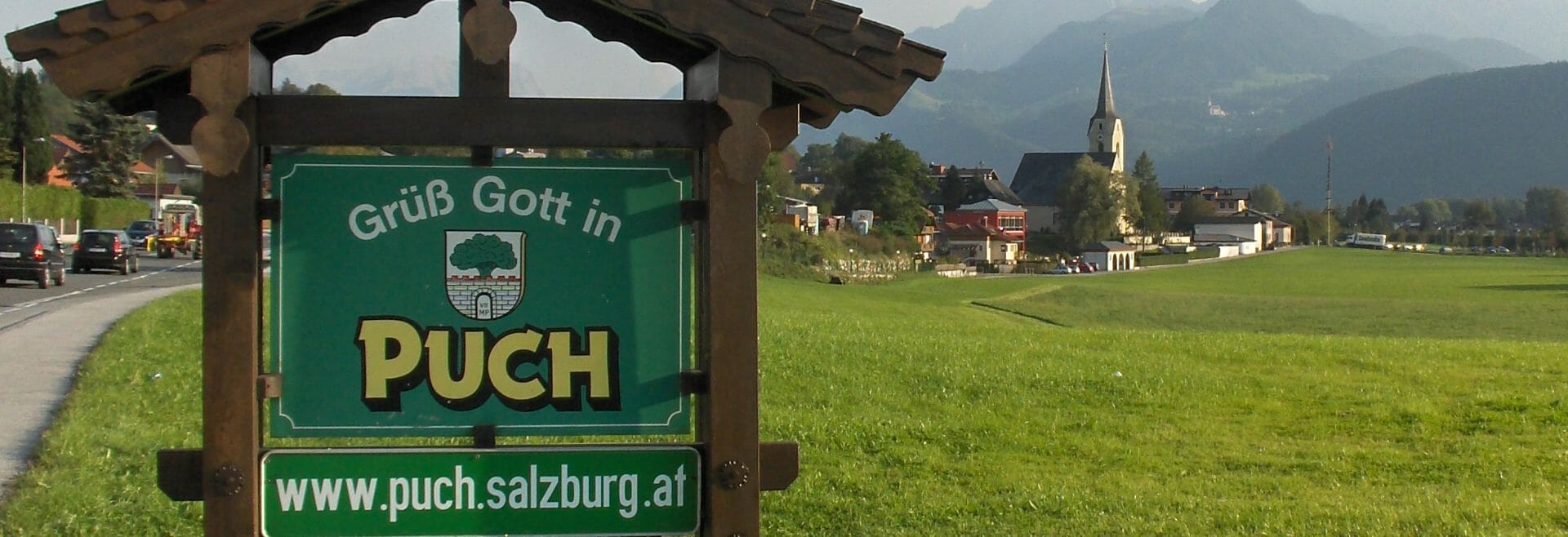Ortsschild von Puch mit der Kirche im Hintergrund
