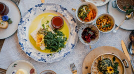 Via Culinaria SalzburgerLand A table set with assorted colourful dishes offers a delightful culinary experience of cheese, salad, and sauces.