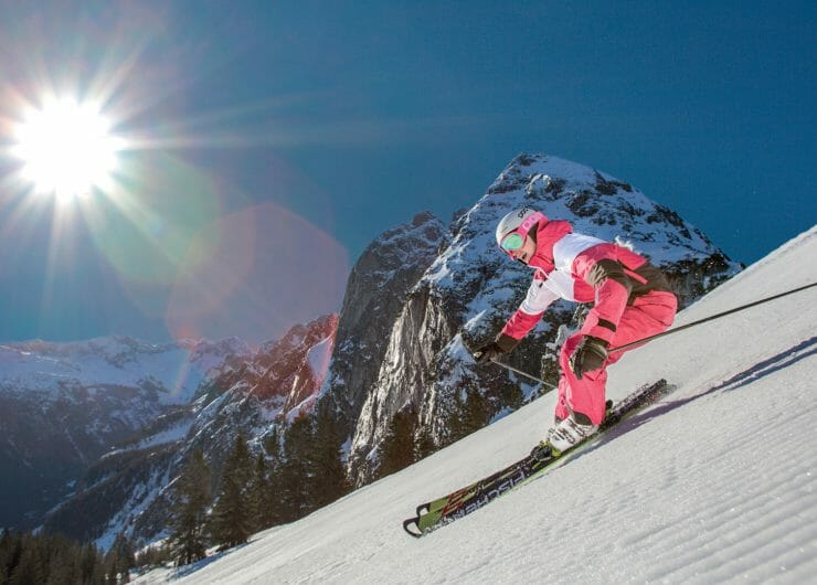 Skifahrer im rot-weißen Overall auf der frisch präparierten Piste