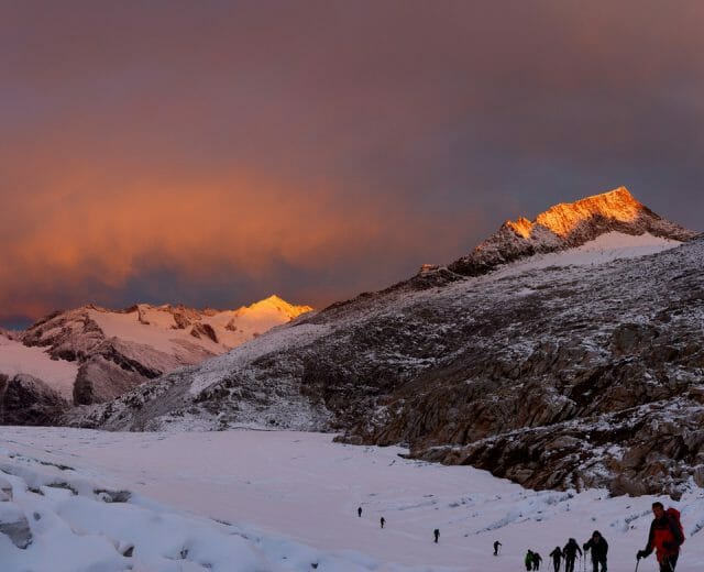 Eine Gruppen von Skitourengehern auf dem Weg nach oben im herrlichen Licht des Sonnenuntergangs.