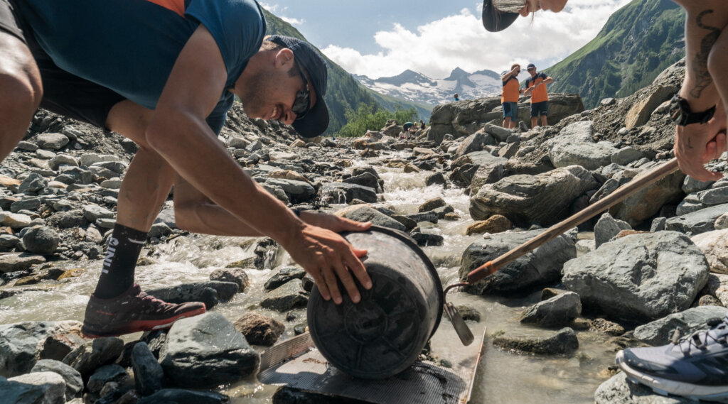 Treasure hunt (c) Peter Maier People clean a rocky Bramberg stream, lifting a bucket and picking up rubbish; mountains are in the background. (Enlarged view)
